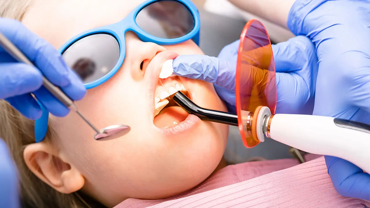 Close up of child getting dental work done by pediatric dental assistant.